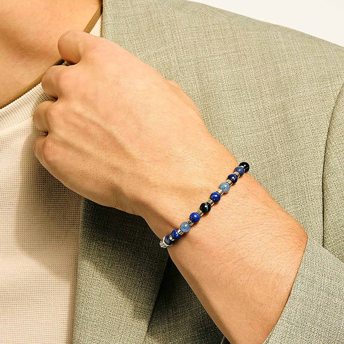 Person wearing a colorful beaded bracelet on a neutral background